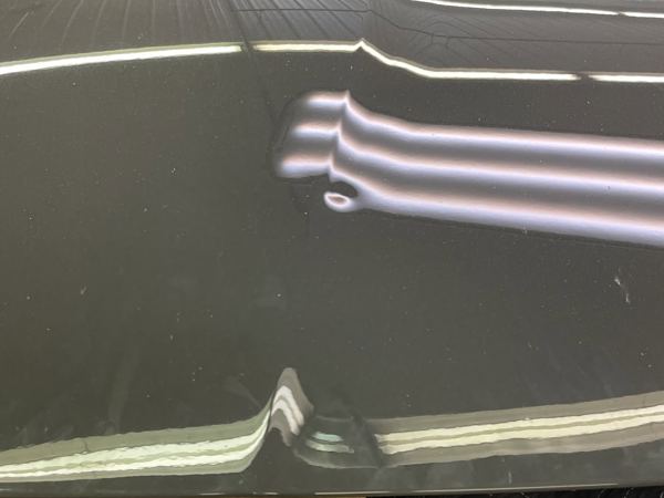 Close-up of the Ferrari hood dent under a PDR light