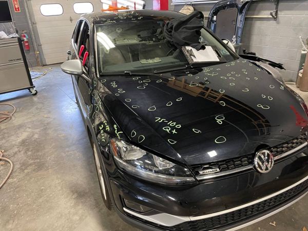 VW Golf Alltrack with hail dents circled on the hood and roof
